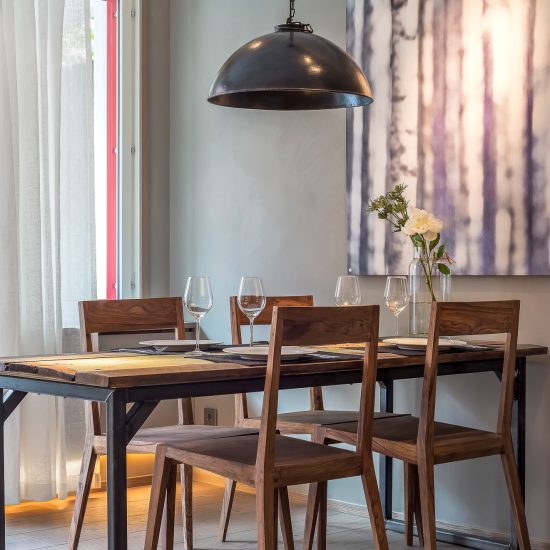 Ett kök inrett med stolar i femtiotalsstil samt en industriell lampa och bord i samma stil.