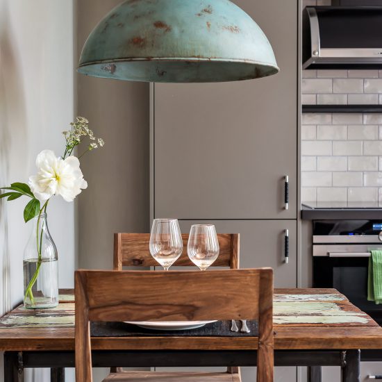 Koppargrön industriell lampa ovanför ett matbord för två i ett modernt inrett kök