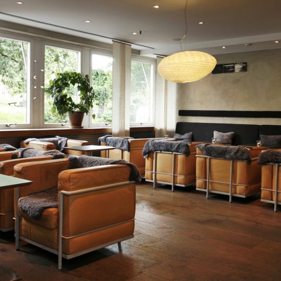 Lounge-stolar i le Corbusier stil och elliptiska lampor i handgjort japanskt papper i en bar.