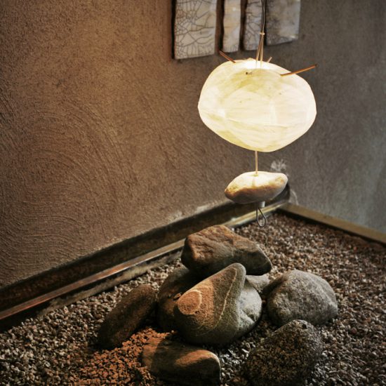 en lampa gjord av handgjort japanskt papper som lyser en betongvägg