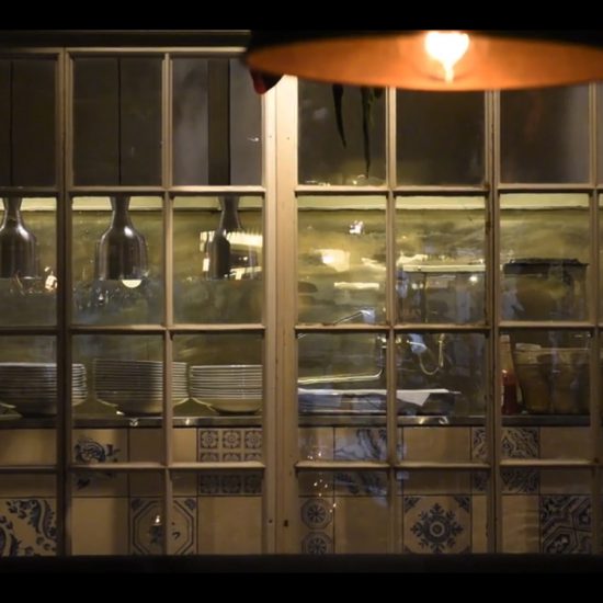 Fönster i sekelskiftesstil som fungerar som skiljevägg mellan kök och restaurang