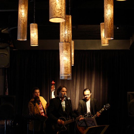 Skräddarsydda lampor som ger en gulaktig ljusbild år en restaurang i bakgrunden spelar en trio jazz