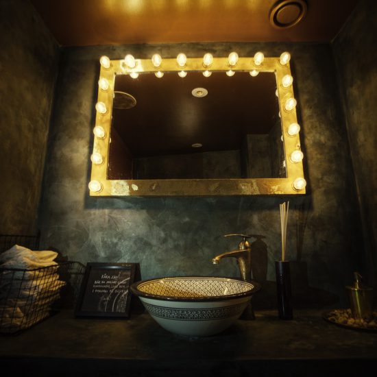Spegel med en ram bestående a lampor, samt ett handfat och vattenkran med klassiska indiska och bengaliska mönster