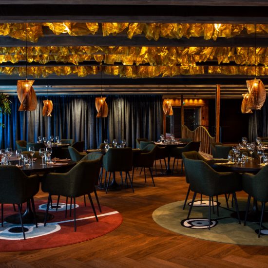 Festsal på restaurang med ett helt tak av sjögräs i mässing designad så att indirekt ljus bjuder in dig.