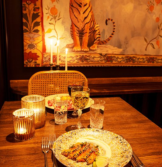 Maträtter serverade på ett ekbord med en målningen av en tiger i bakgrunden